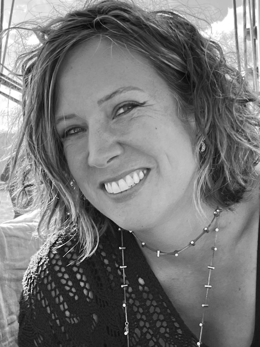 Portrait en noir et blanc de Maya Lahouel, souriante, sur un voilier.